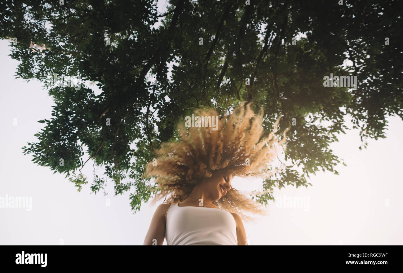 Young woman with blond ringlets tossing her hair Stock Photo