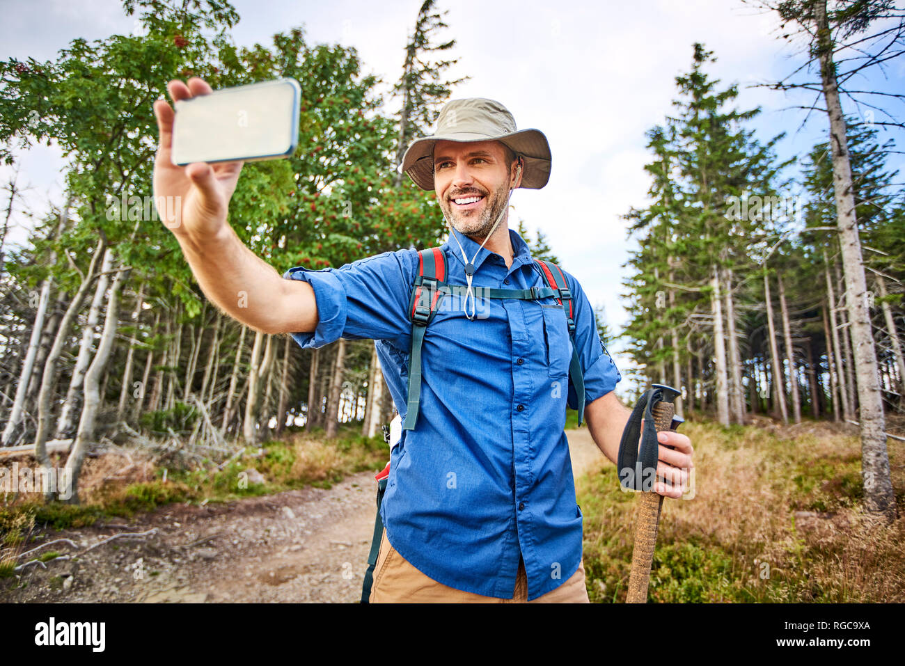 Man taking a selfie with his cell phone during hiking trip Stock Photo