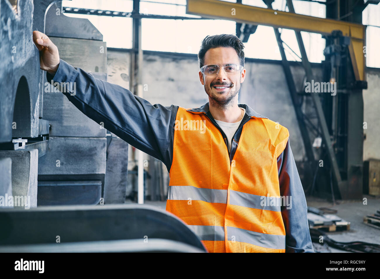 Portrait of smiling man wearing protective workwear in factory Stock Photo