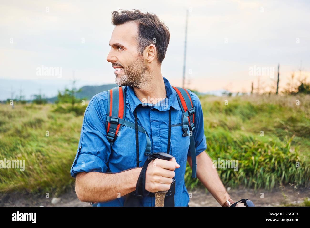 Smiling man hiking in the mountains turning round Stock Photo