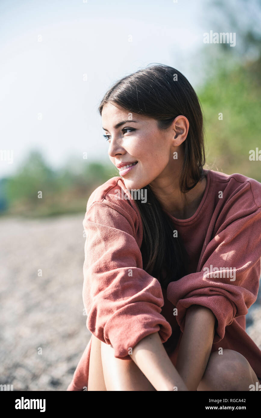 Smiling young woman sitting outdoors Stock Photo