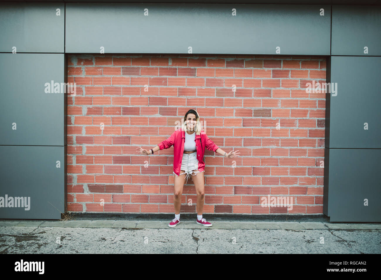 Casual young woman in front of a brick wall Stock Photo - Alamy