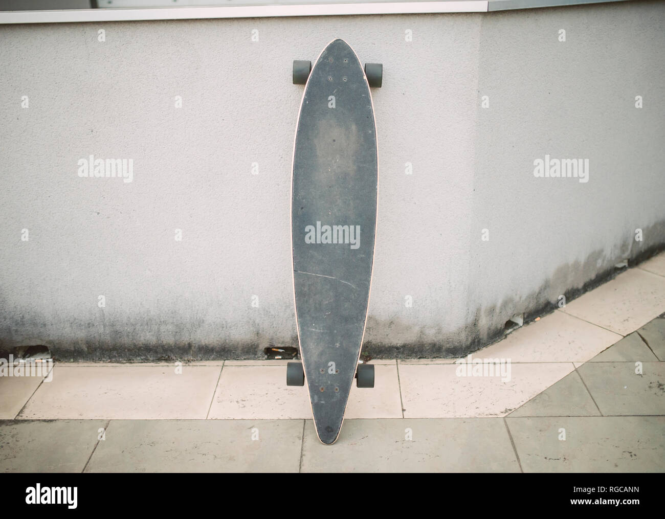 Longboard in the street leaning against a wall Stock Photo Alamy