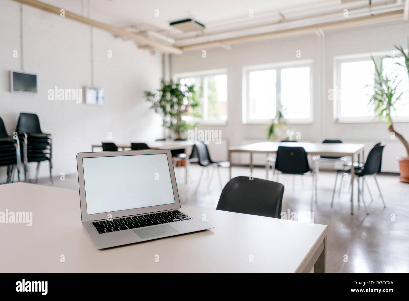 Laptop with blank screen on desk in board room Stock Photo
