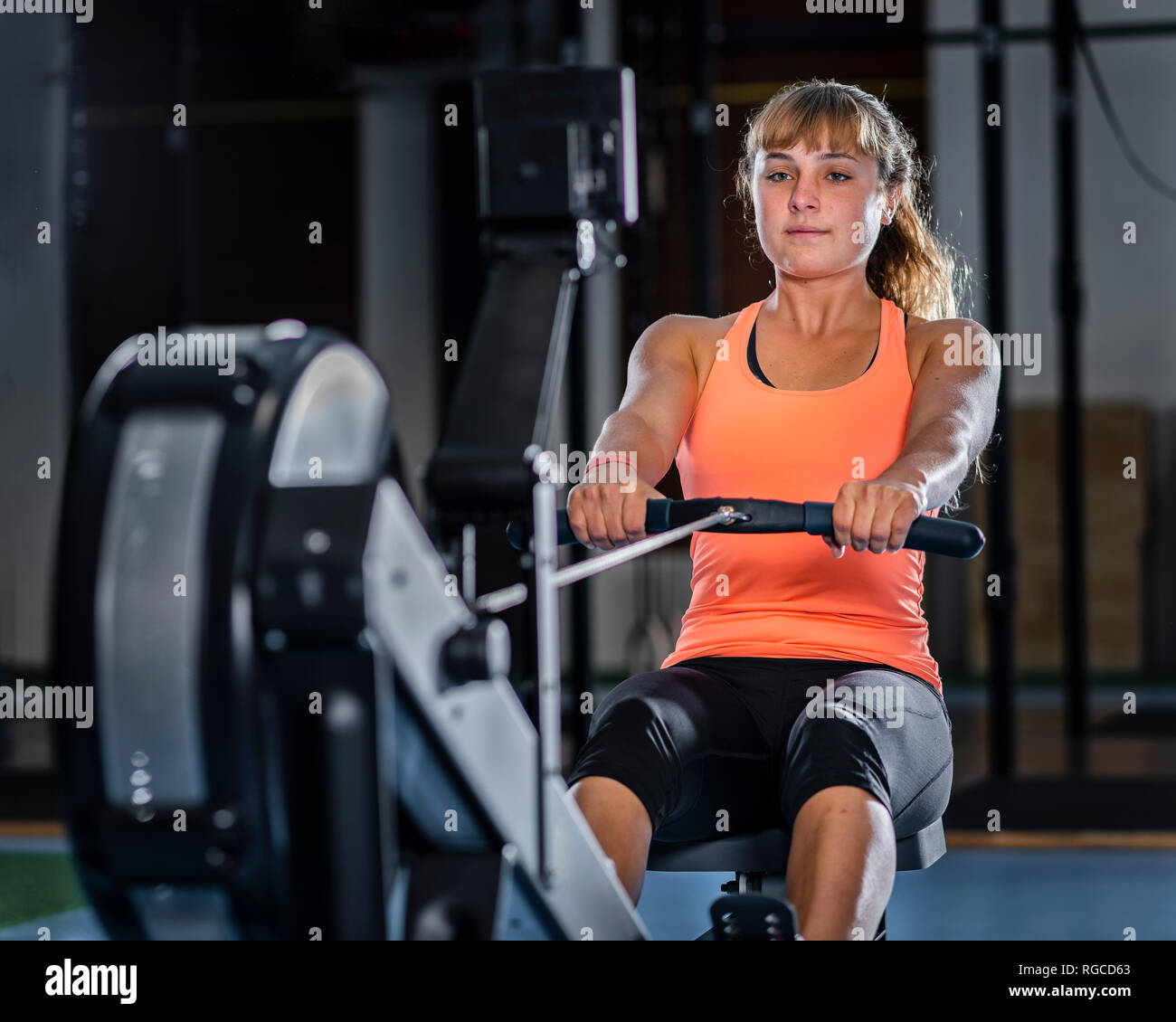 Athletic young woman exercising with rowing machine at gym Stock Photo