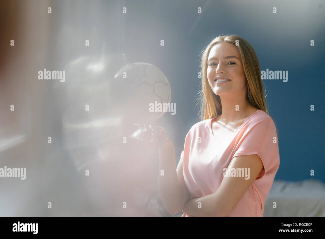 Portrait of smiling young woman with globe Stock Photo