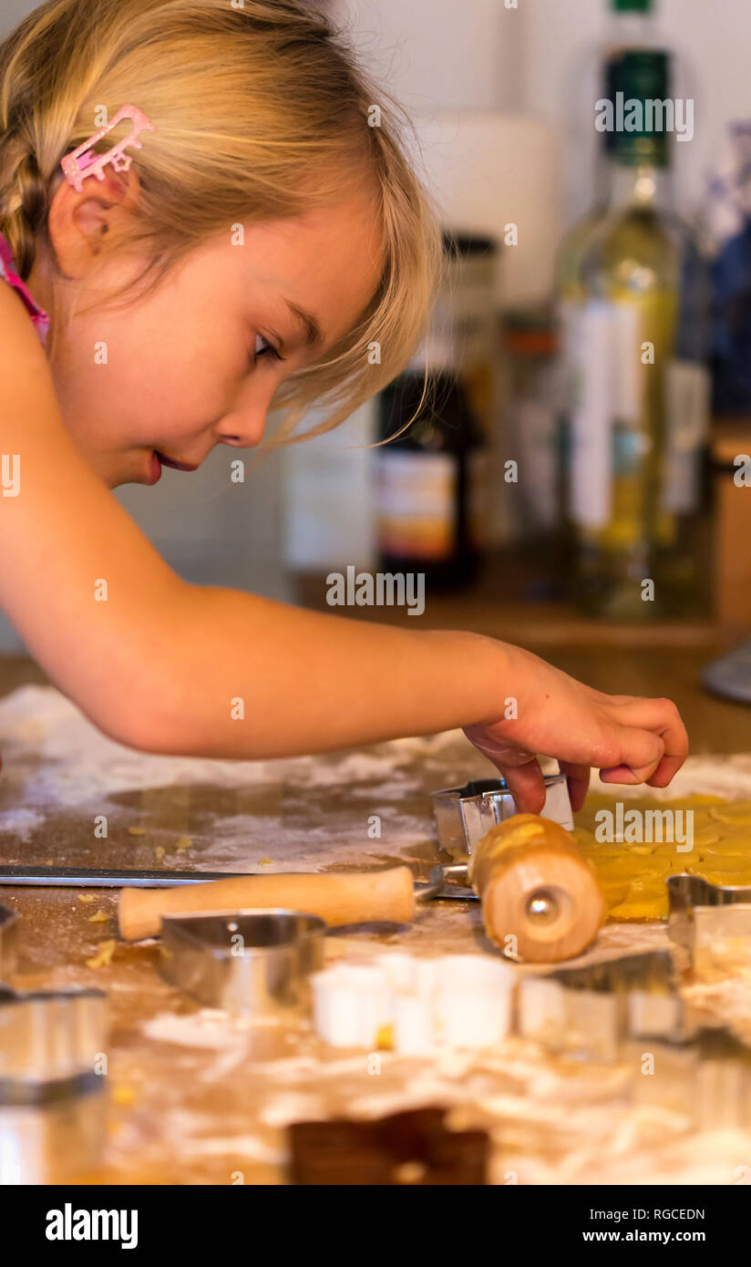 Little girl cutting out cookies with cookie cutter at Christmas time Stock Photo