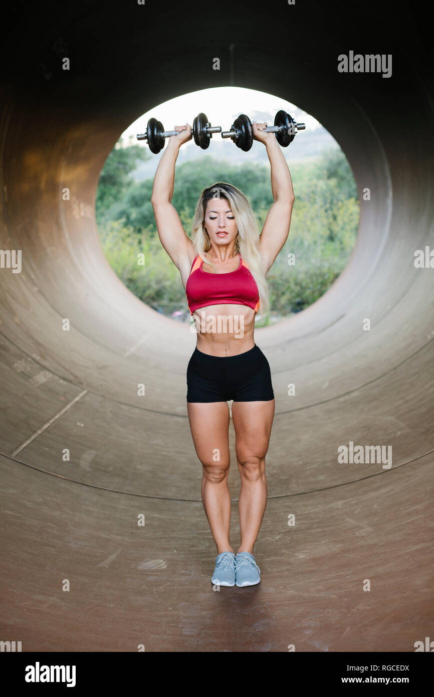 Athletic woman doing weight workout standing inside a tube Stock Photo