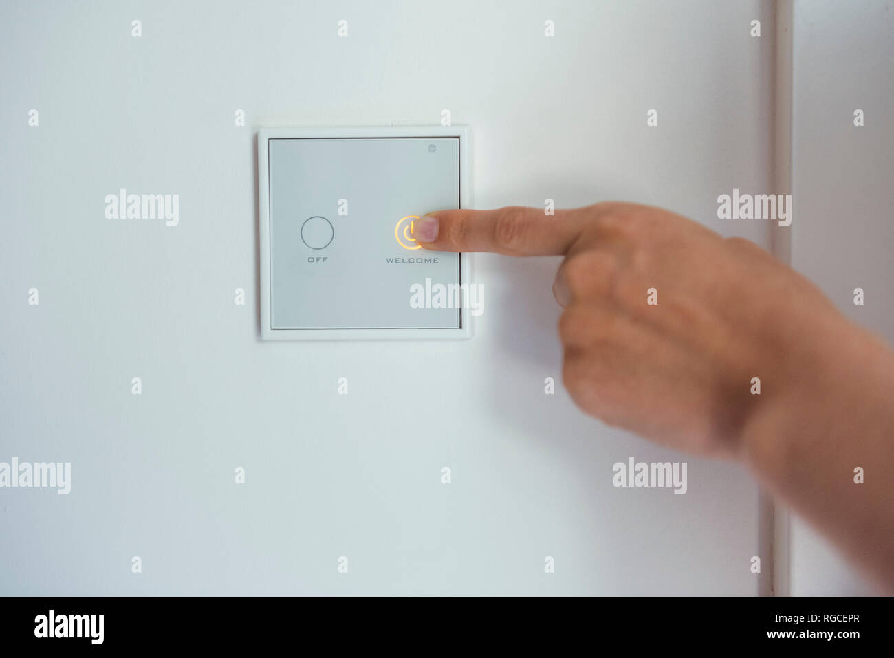 Woman using smart home switch on wall Stock Photo