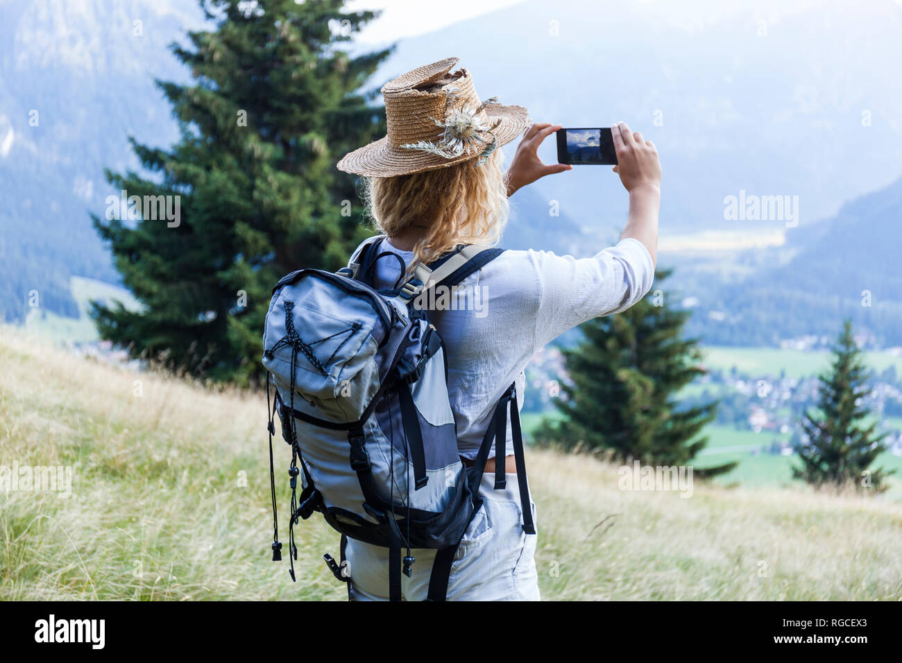Young Woman Hiking Taking Cell Phone Picture Mountain Meadow Hi res young-woman-hiking-taking-cell-phone-picture-mountain-meadow-hi-res