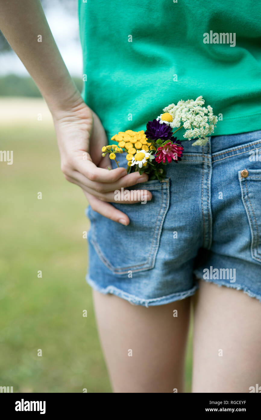 Flowers in pocket of girl's jeans shorts Stock Photo