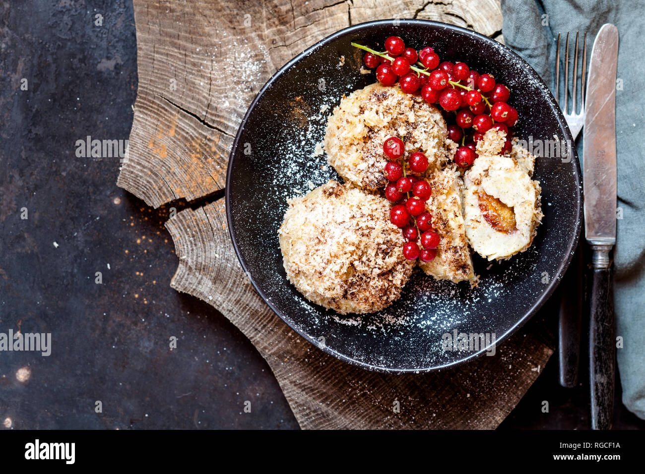 Plum filled sweet dumplings with coconut-cinnamon crust and redcurrants Stock Photo