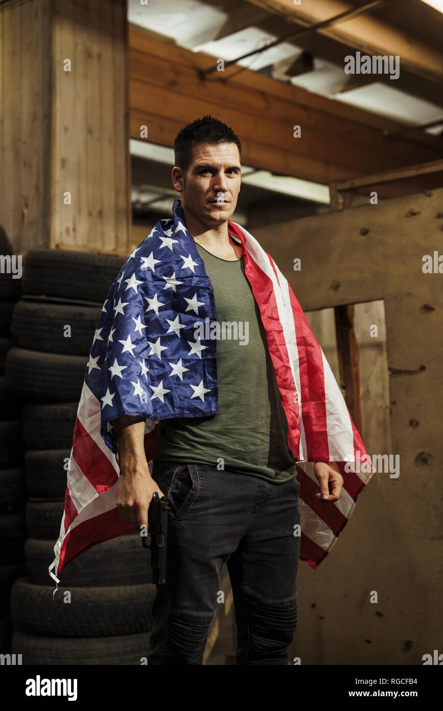 Portrait of man wearing American flag holding a gun Stock Photo