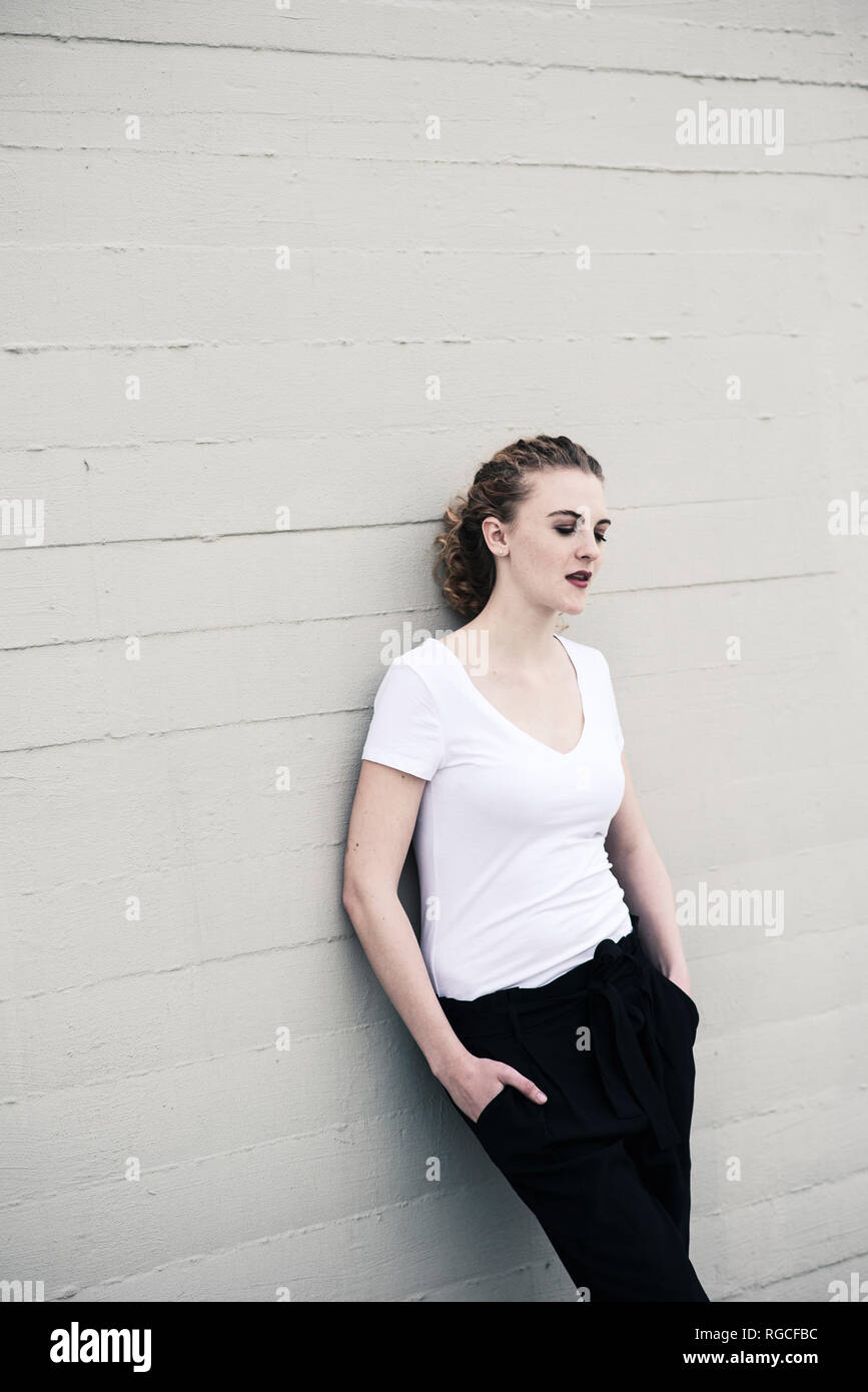 Portrait of cool young woman leaning against wall Stock Photo