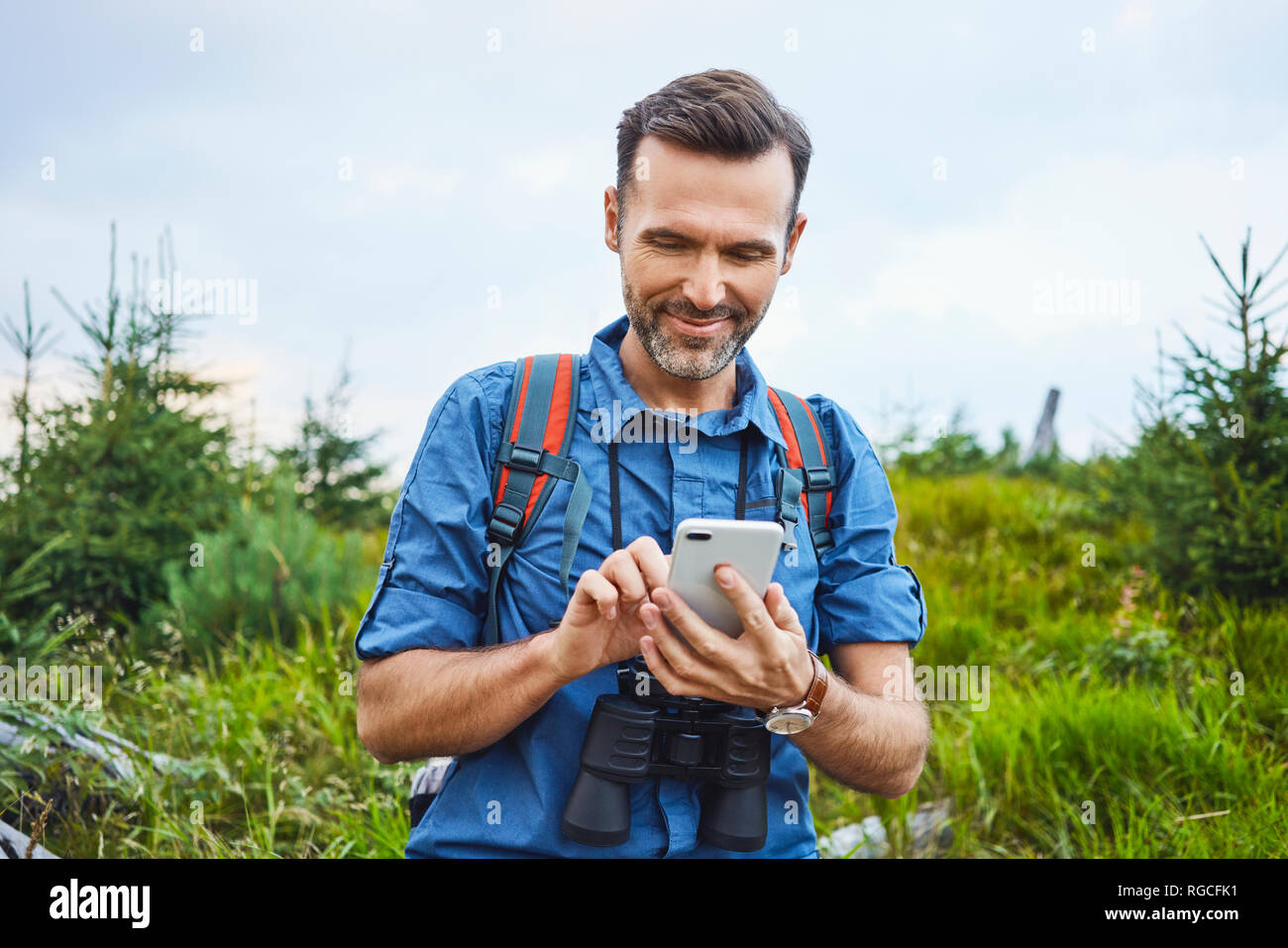 Smiling man checking his cell phone during hiking trip Stock Photo