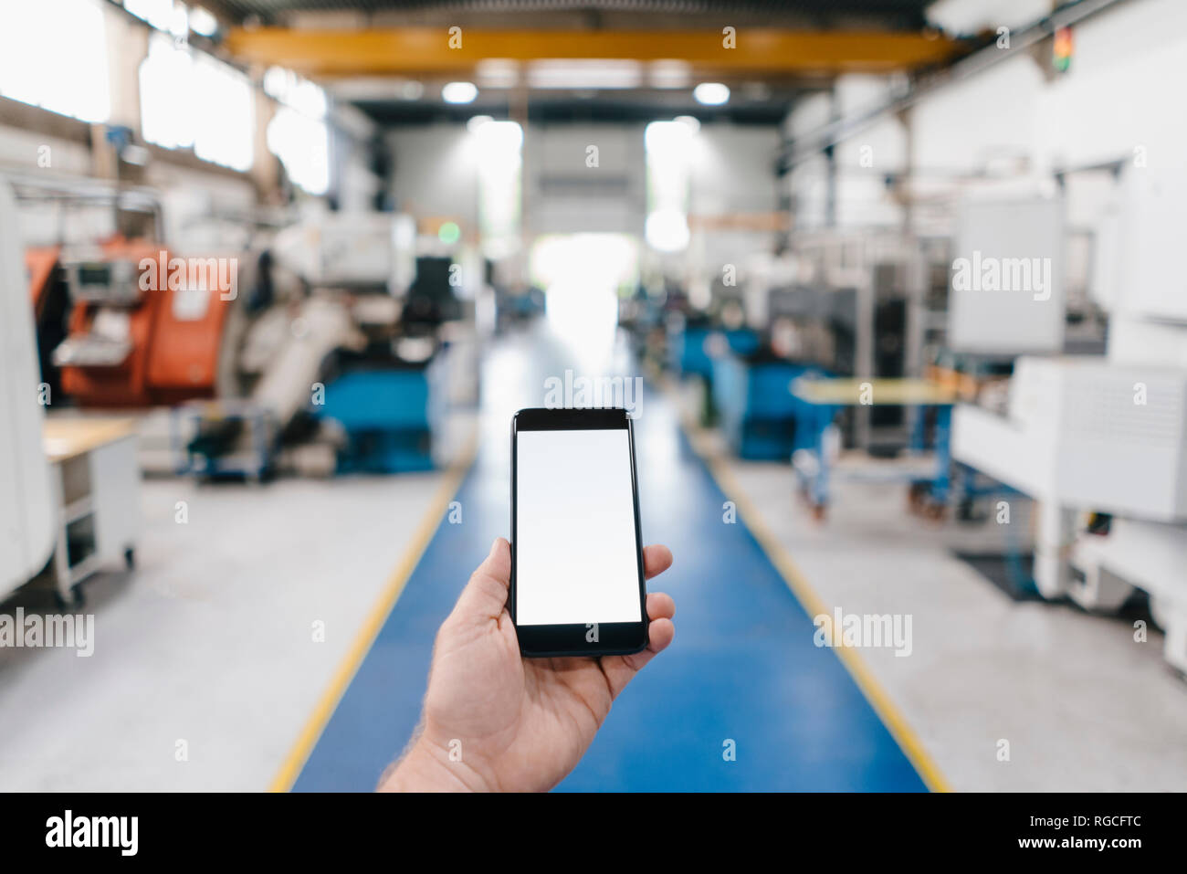 Hand holding smartphone with blank screen in a factory workshop Stock ...