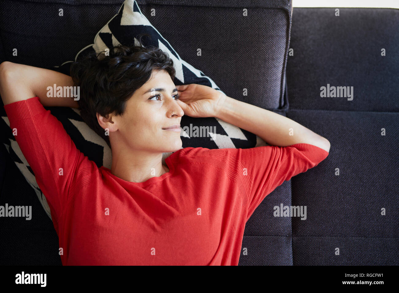 Portrait of smiling woman lying on couch at home Stock Photo - Alamy