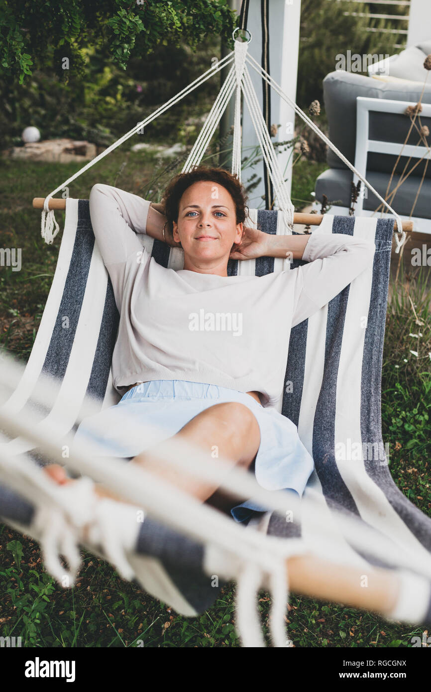 Portrait of smiling woman lying in a hammock Stock Photo - Alamy