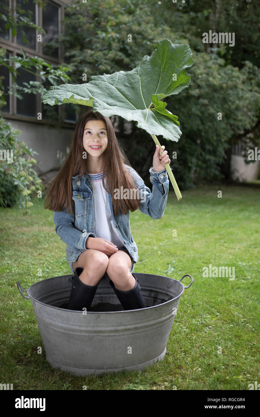 Portrait of smiling girl sitting under big in tub in in the garden Stock Photo