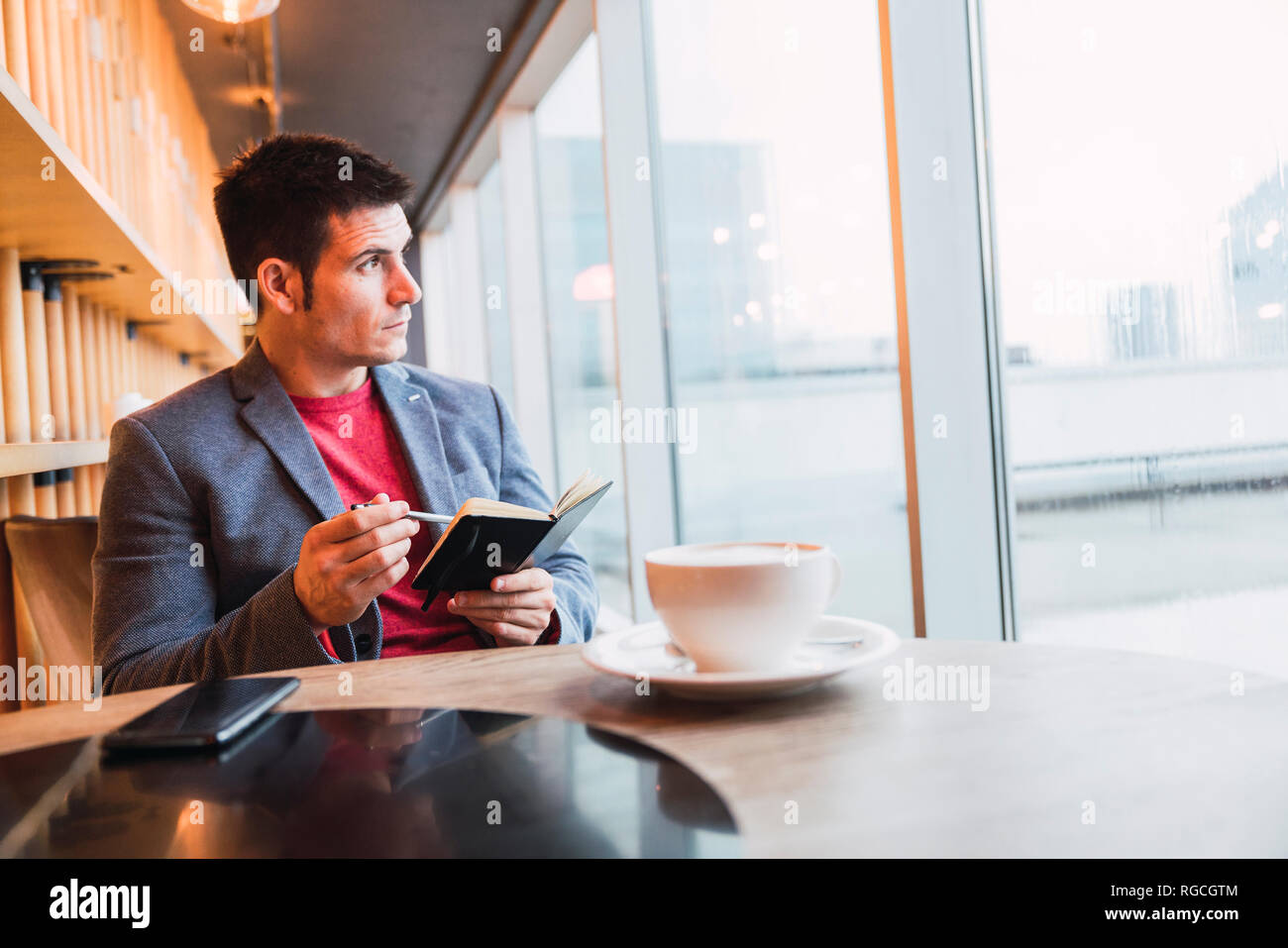 Businessman sitting in restaurant drinking coffee and checking his notebook Stock Photo
