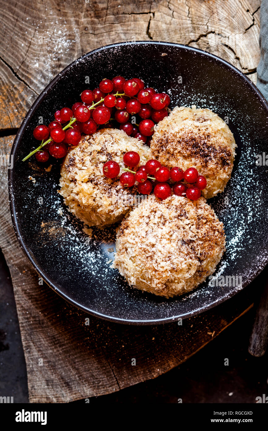 Plum filled sweet dumplings with coconut-cinnamon crust and redcurrants Stock Photo
