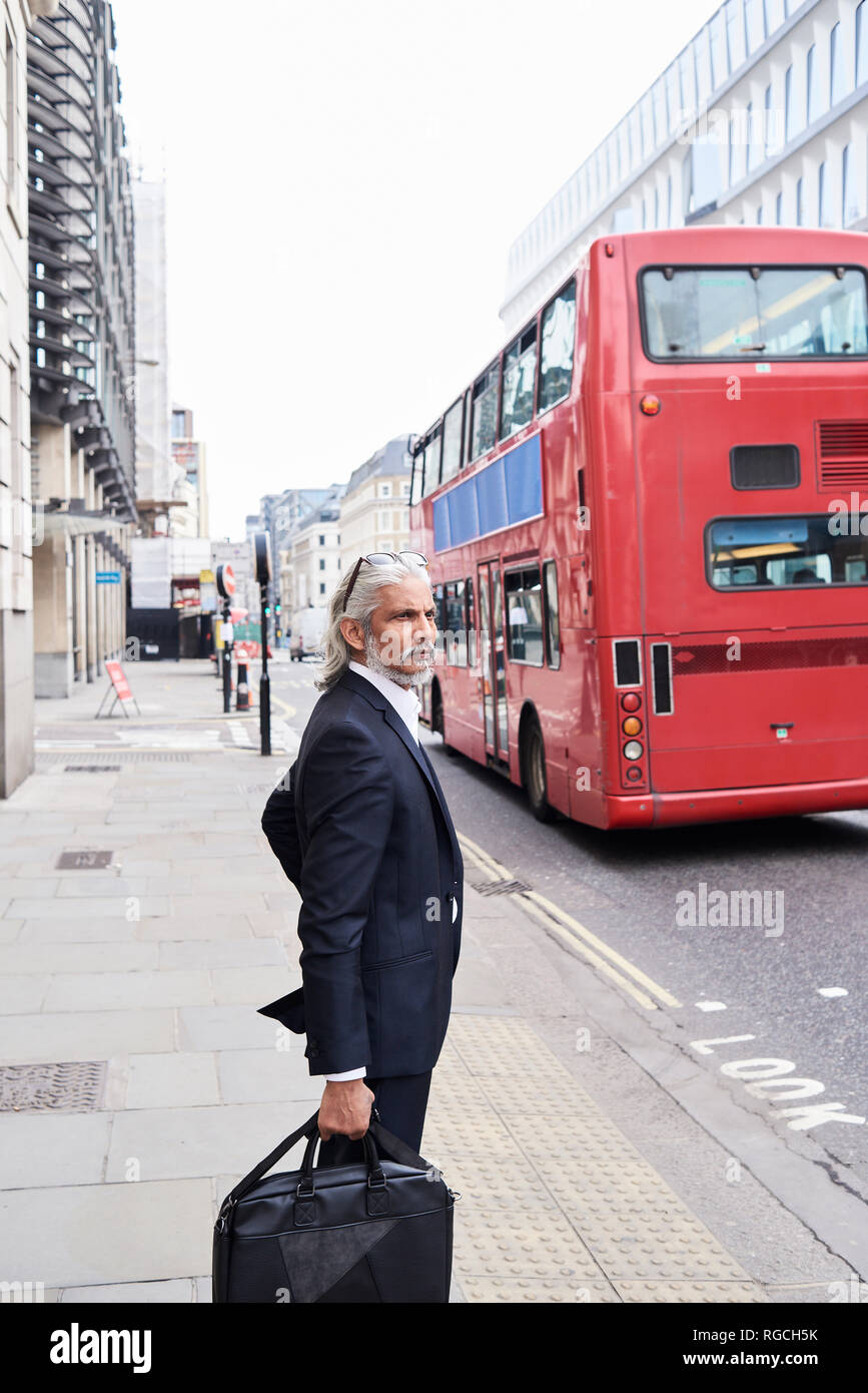 UK, London, senior businessman with luggage waiting at crosswalk Stock Photo