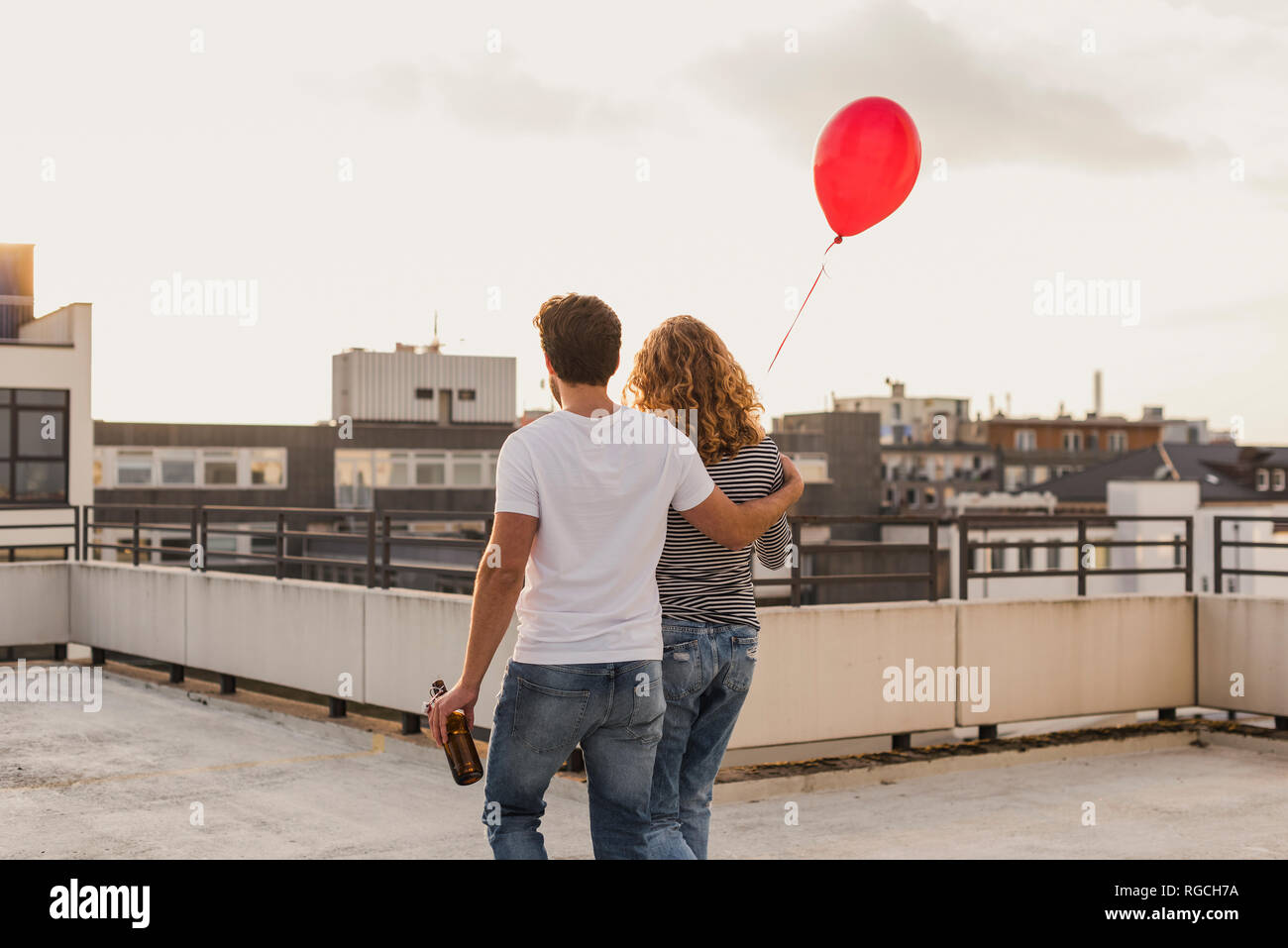 Back view of young couple on roof terrace at evening twilight Stock Photo