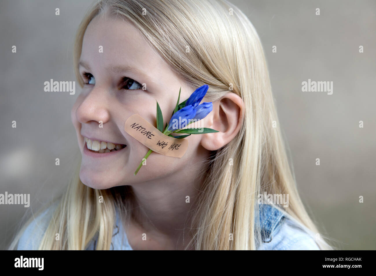 Portrait of smiling blond girl with flower head on her cheek Stock