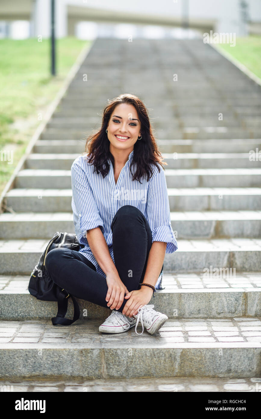 Portrait of smiling student sitting on stairs outdoors Stock Photo - Alamy