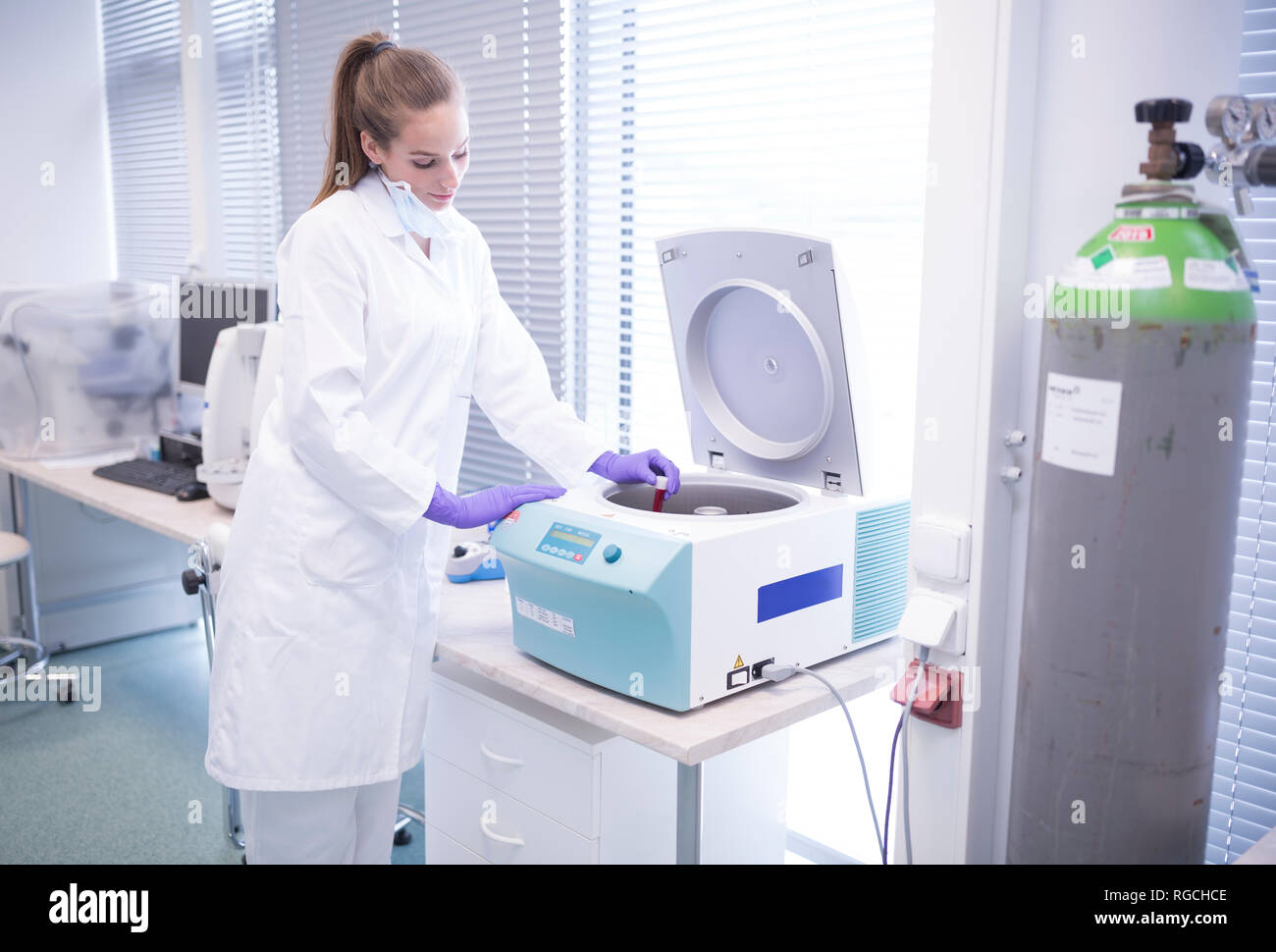 Scientist in lab putting blood sample into centrifuge Stock Photo