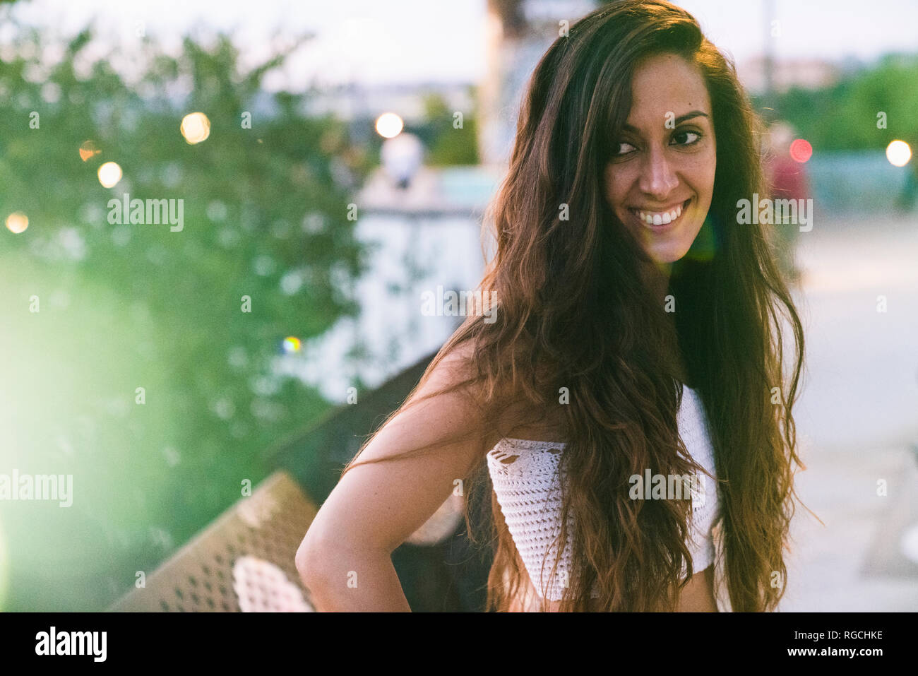 Portrait of beautiful smiling young woman with long brown hair outdoors ...