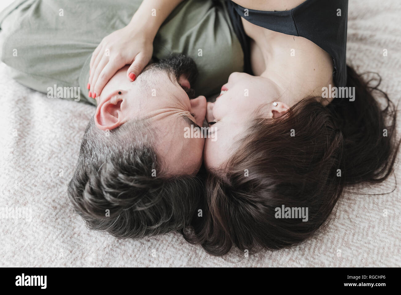 Couple lying on bed, kissing, cuddling and embracing Stock Photo