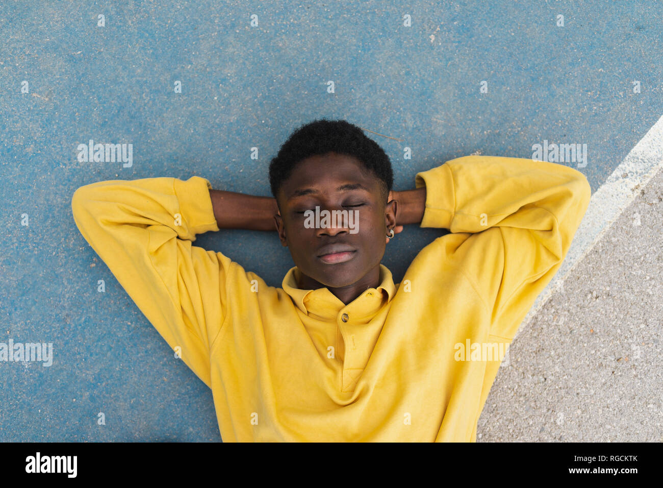 Young black man sleeping on floor, with hands behind head Stock Photo