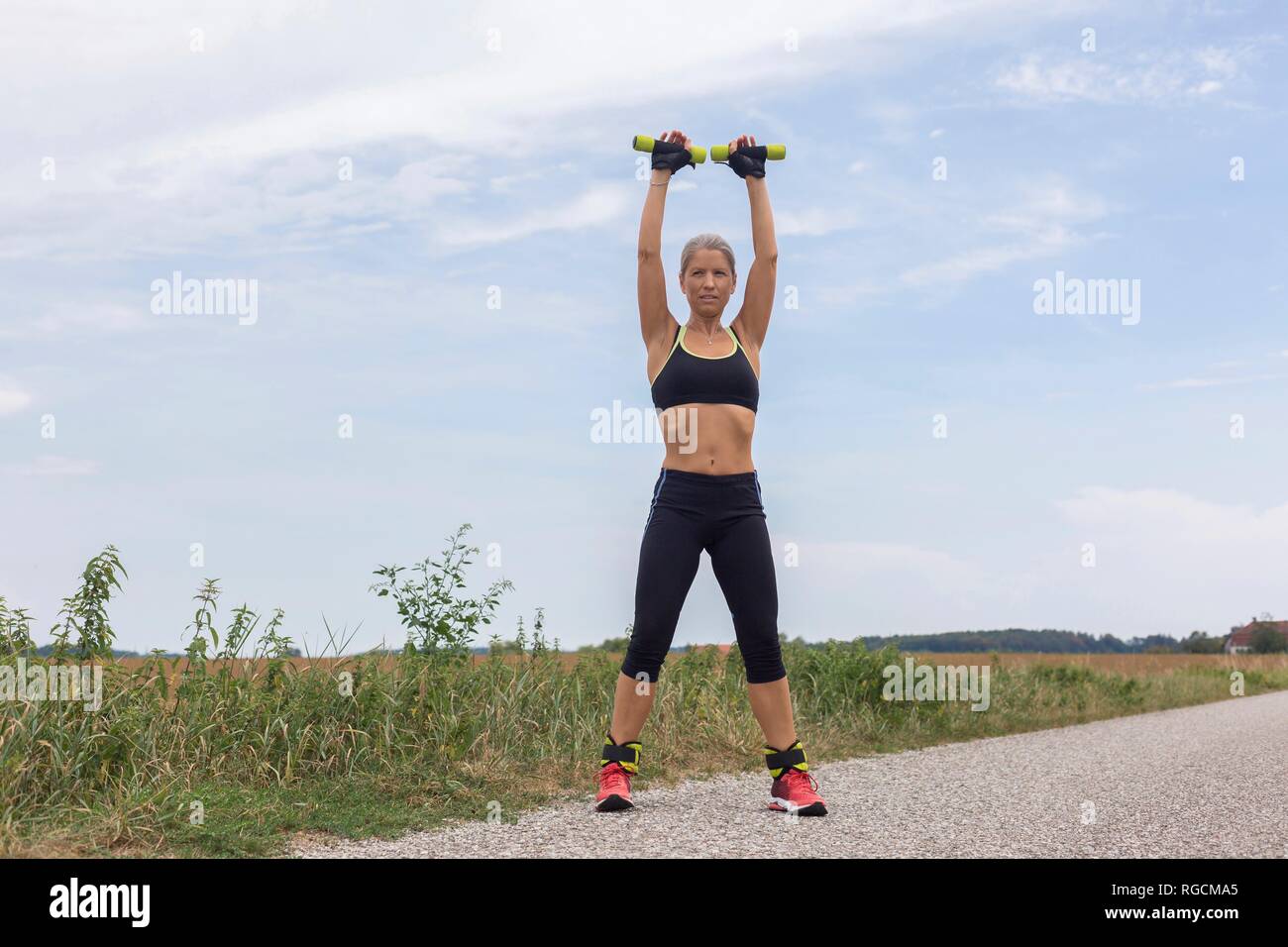 Mature woman doing workout on remote country lane in summer Stock Photo