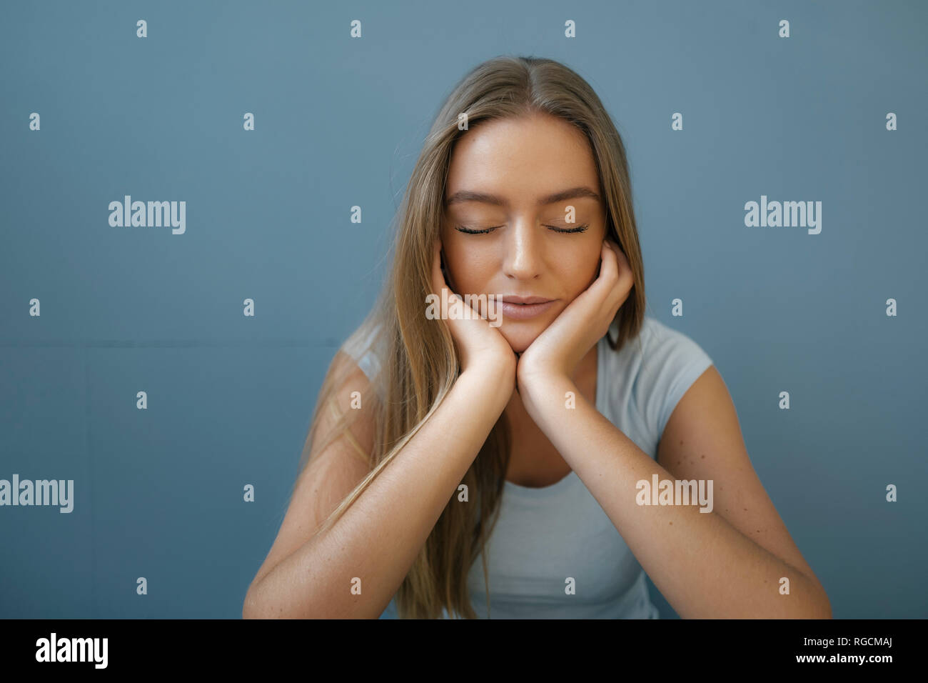 Portrait of young woman with eyes closed and head in hands relaxing Stock Photo
