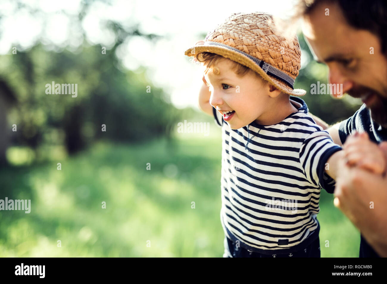 Father assisting little boy in balancing outdoors Stock Photo