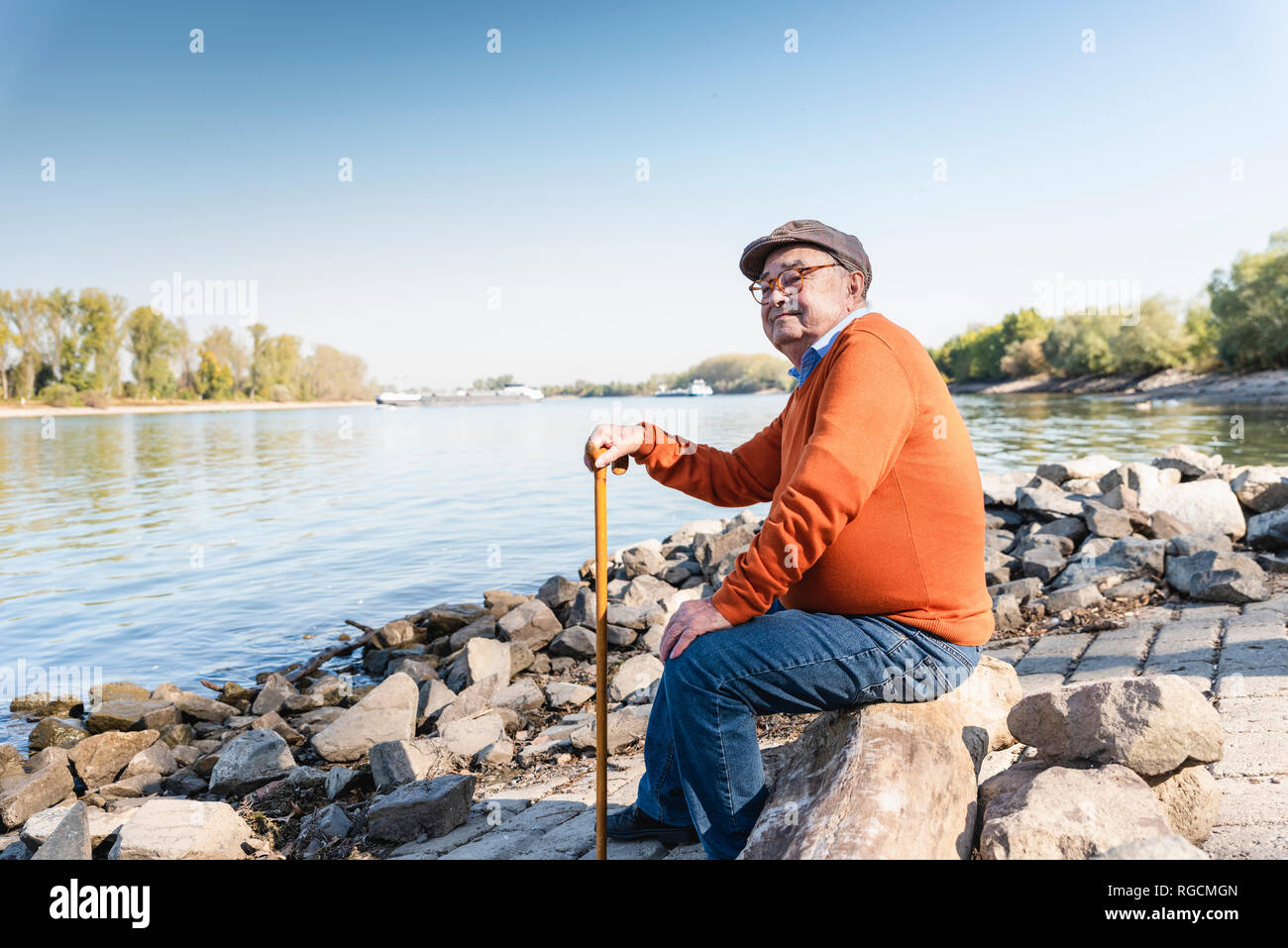 Old man sitting by the river Stock Photo