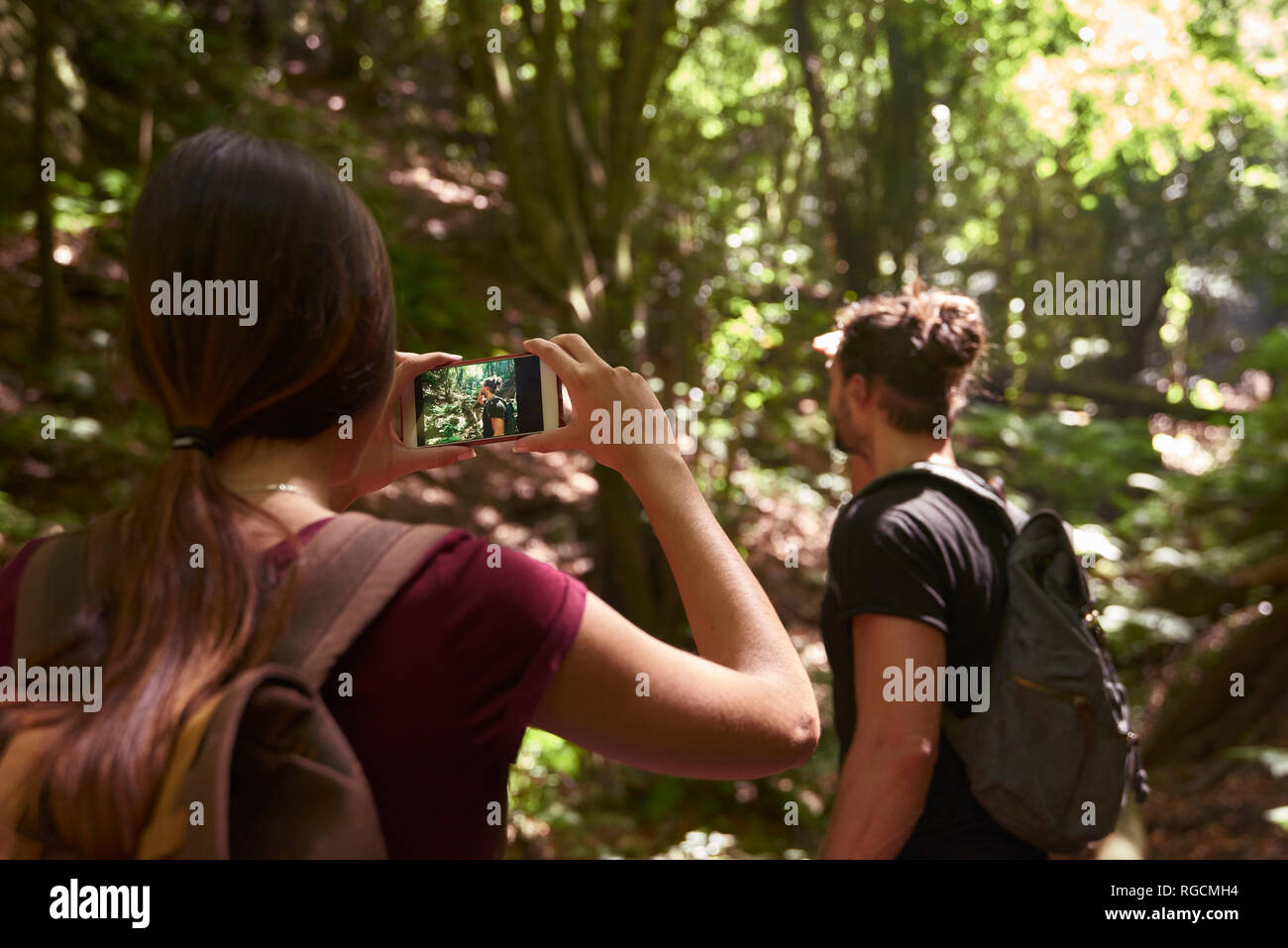 Spain, Canary Islands, La Palma, woman taking a cell phone picture of her boyfriend in a forest Stock Photo