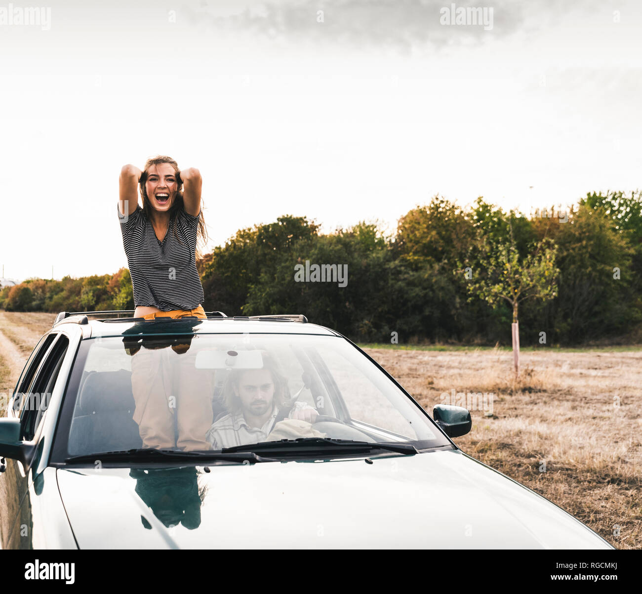 Carefree young woman looking out of sunroof of a car Stock Photo