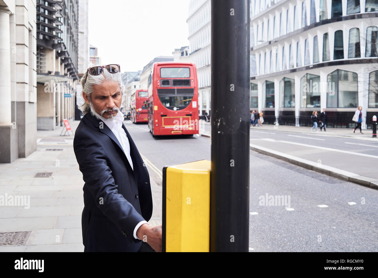 UK, London, bearded senior businessman pressing traffic lights button Stock Photo