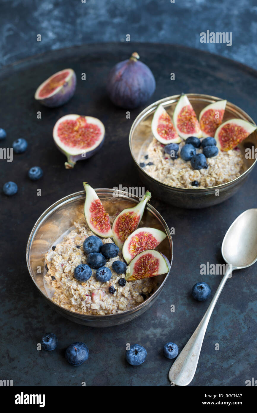 Bowls of porridge with sliced figs, blueberries and dried berries Stock Photo