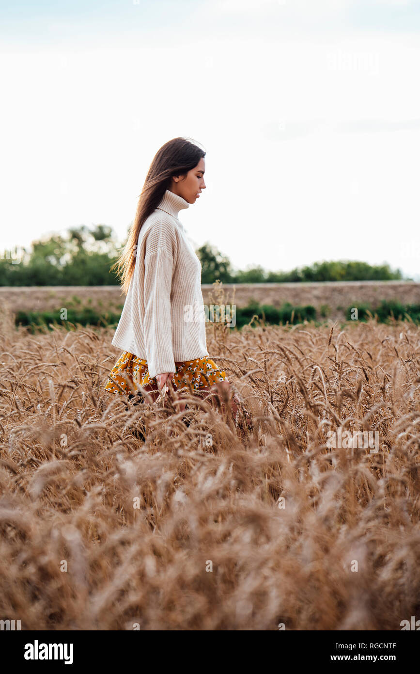 Young woman wearing oversized turtleneck pullover standing in corn field Stock Photo