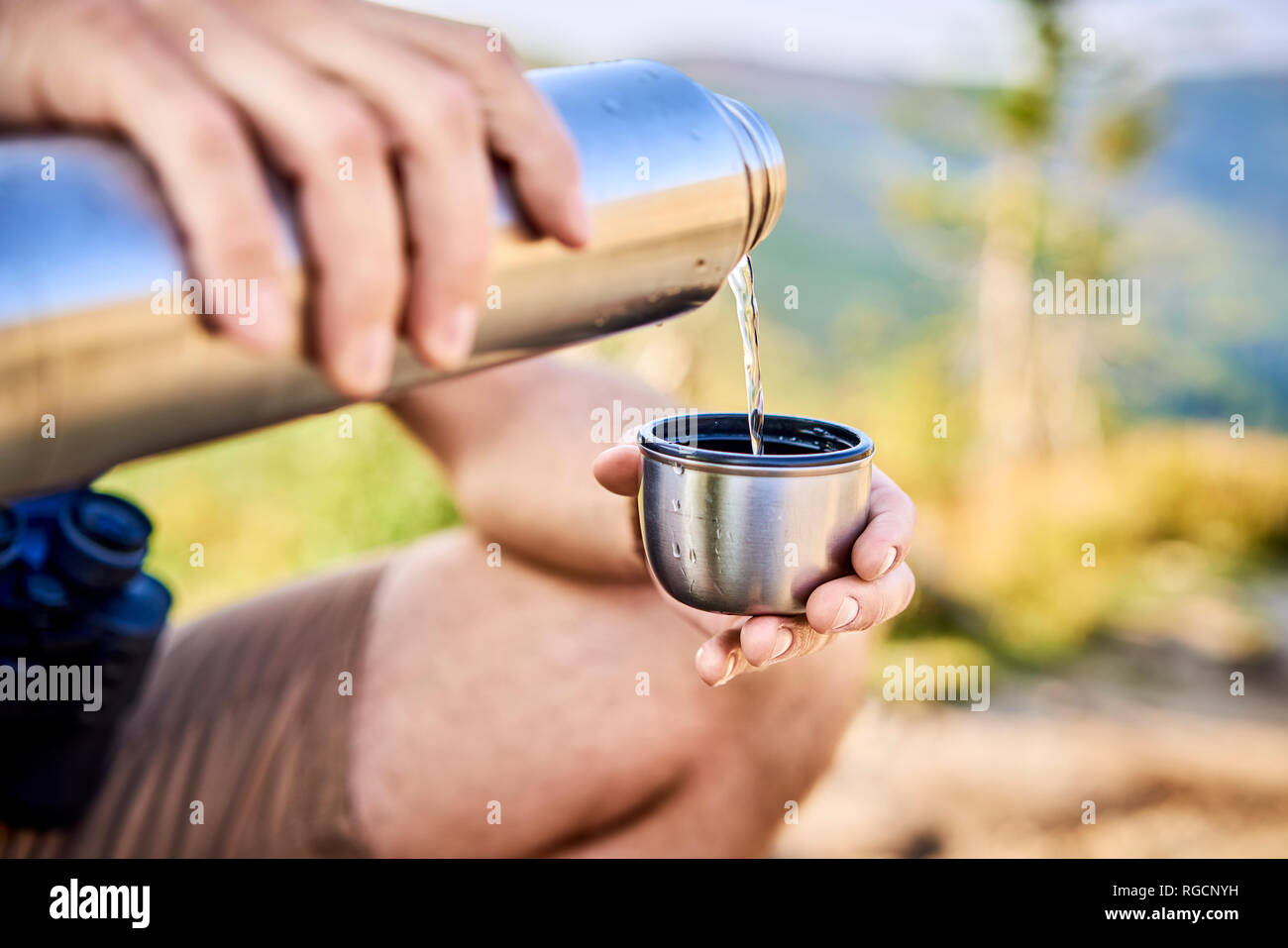 Close-up of man during hiking trip pouring cold water from thermos flask Stock Photo