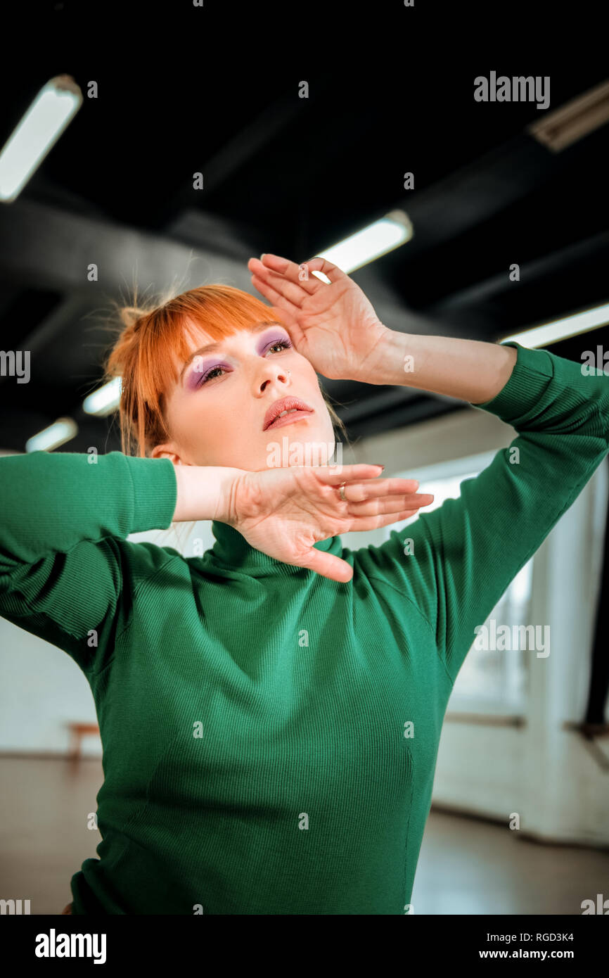 Young red-haired professional choreographer with bright makeup looking thoughtful Stock Photo