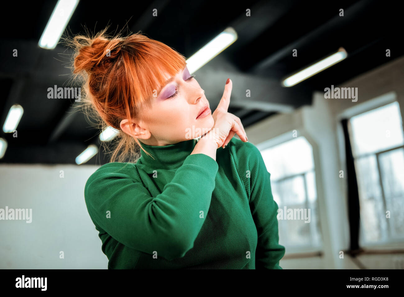 Red-haired professional choreographer with hair bun feeling relaxed Stock Photo