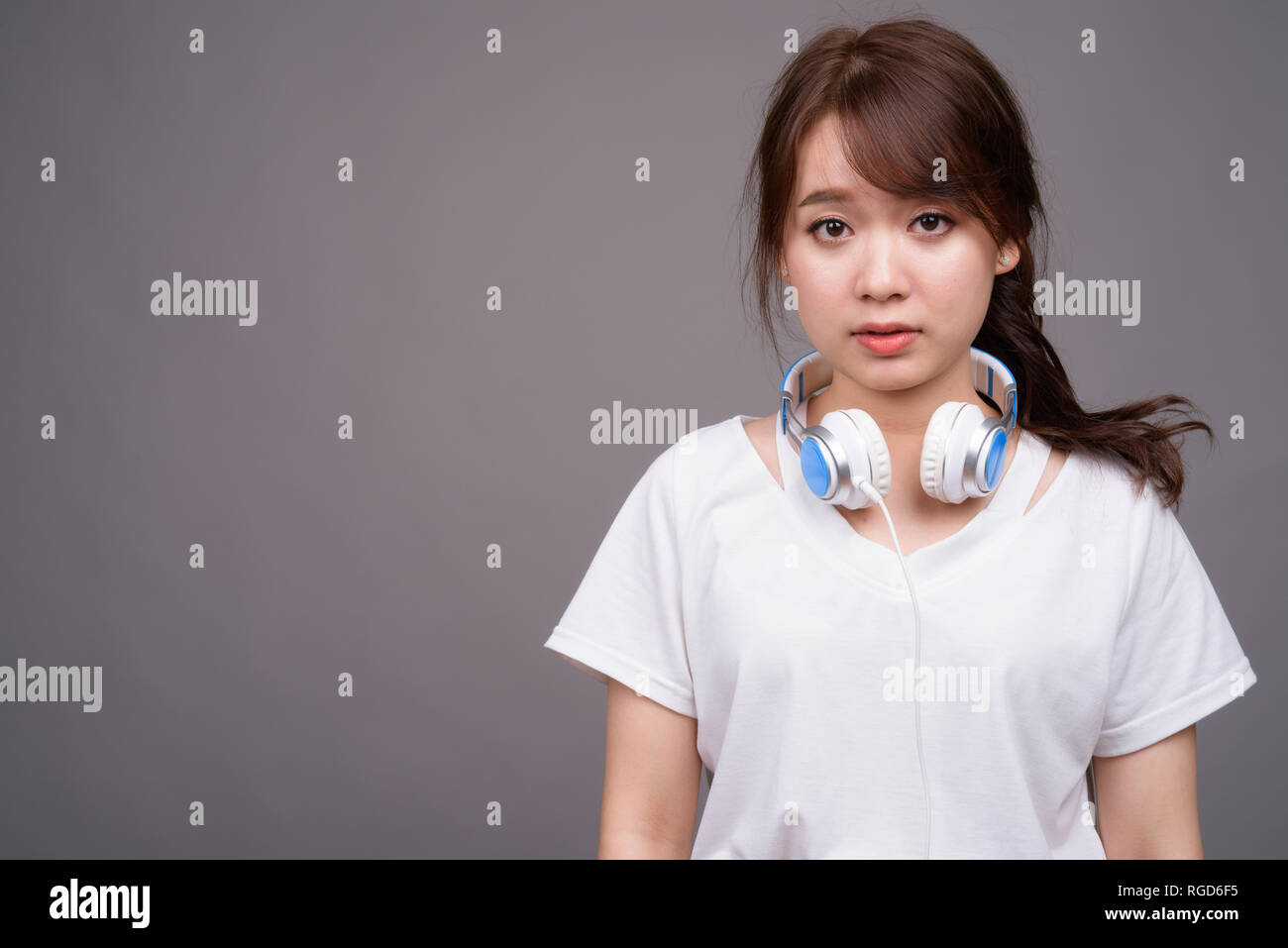 Young beautiful Asian woman wearing headphones for music Stock Photo