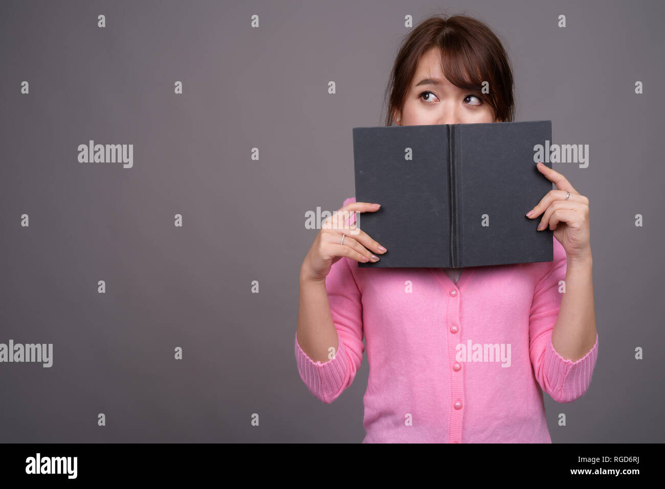 Young beautiful Asian woman holding book or diary Stock Photo