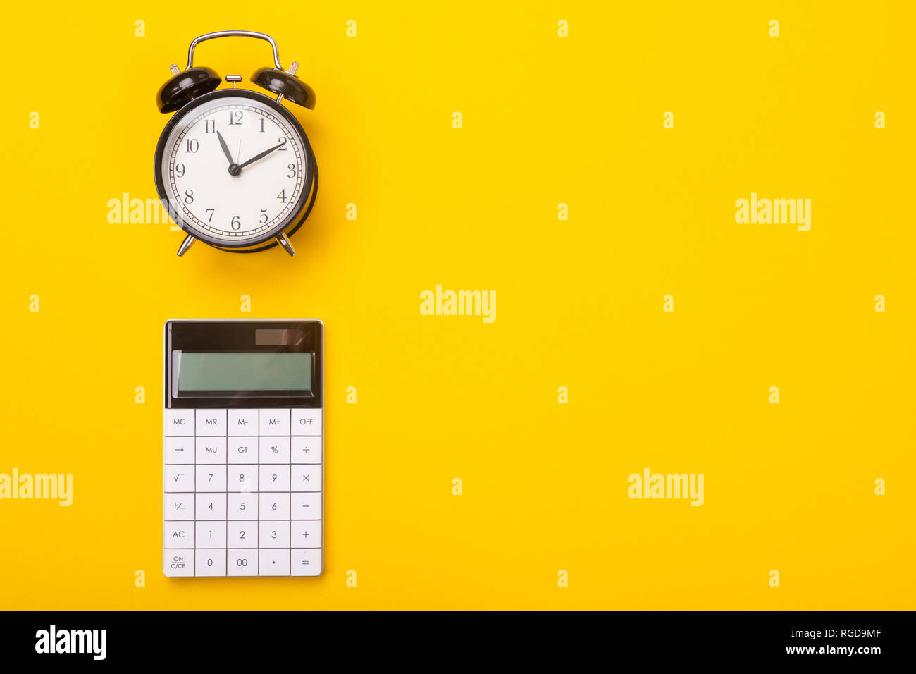 dial of the alarm clock and stylish modern calculator lie isolated on the  side of the yellow table. Place for writing. Can be used as a business  backg Stock Photo - Alamy