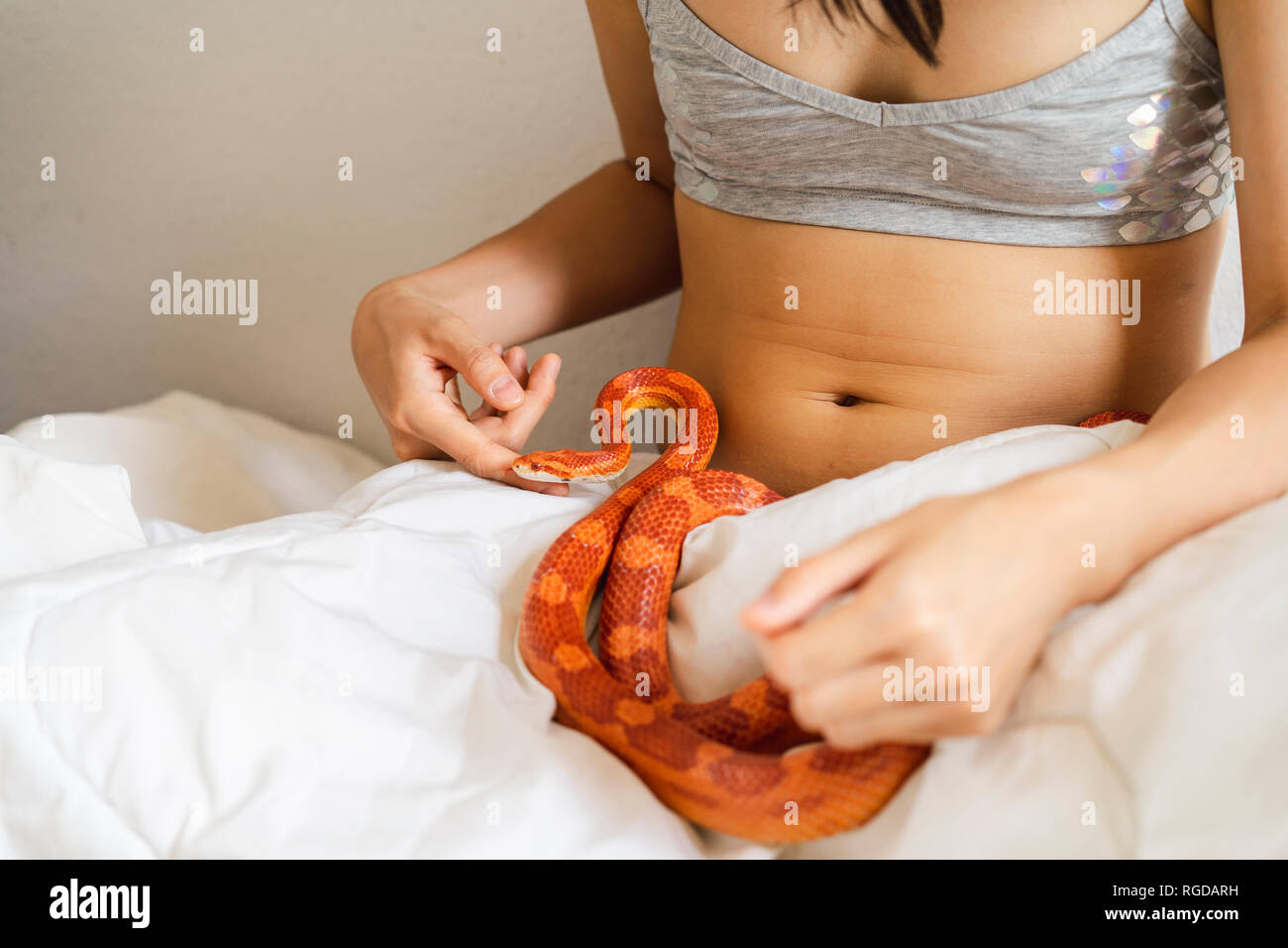 Young woman in bed with a snake Stock Photo