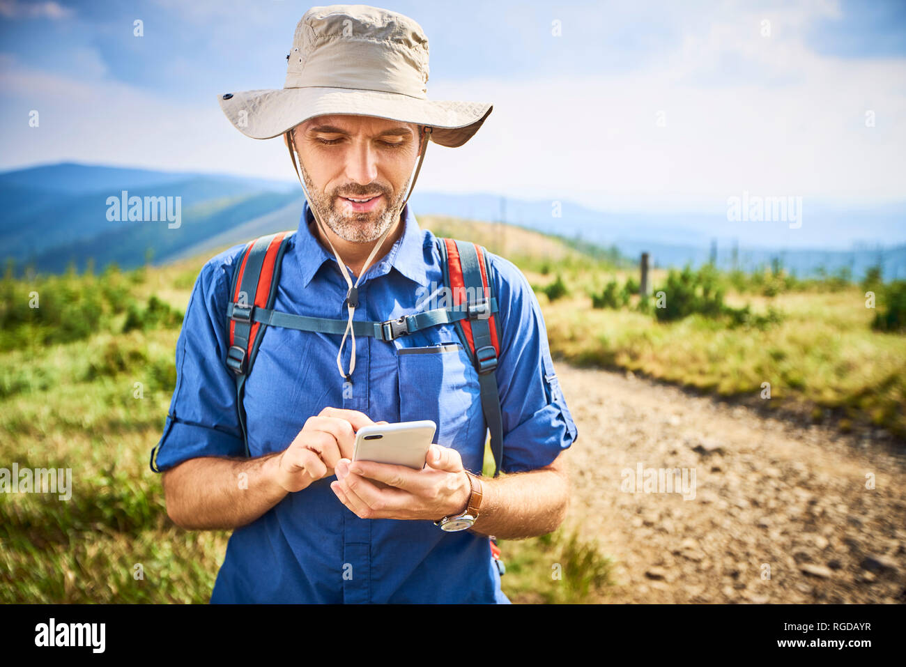 Man checking his cell phone during hiking trip Stock Photo